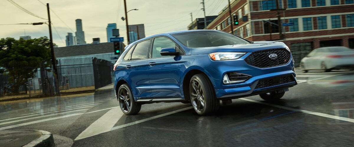 2019 Ford Edge A blue 2019 Ford Edge driving through an intersection in a city