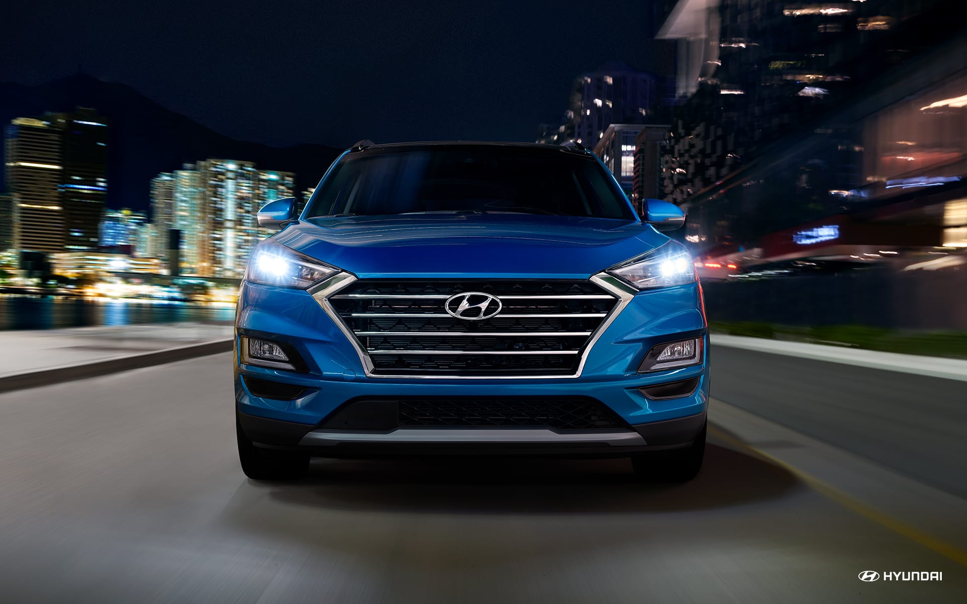Blue 2020 Hyundai Tucson driving down a busy city street at night. Available now at Kearny Mesa Hyundai