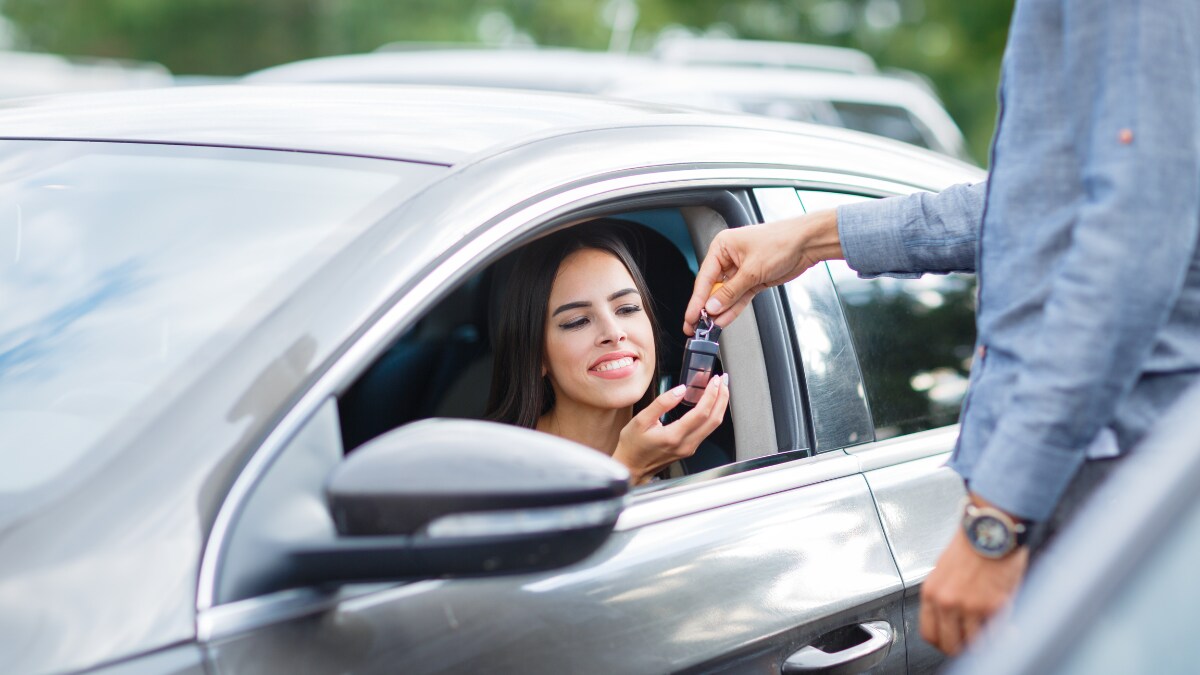 Smiling young woman getting the keys to her used car Smiling young woman getting the keys to her used car