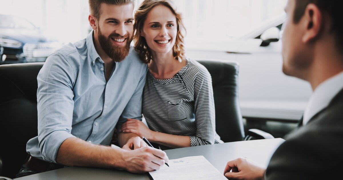 Happy couple signing a vehicle finance agreement Happy couple signing a vehicle finance agreement