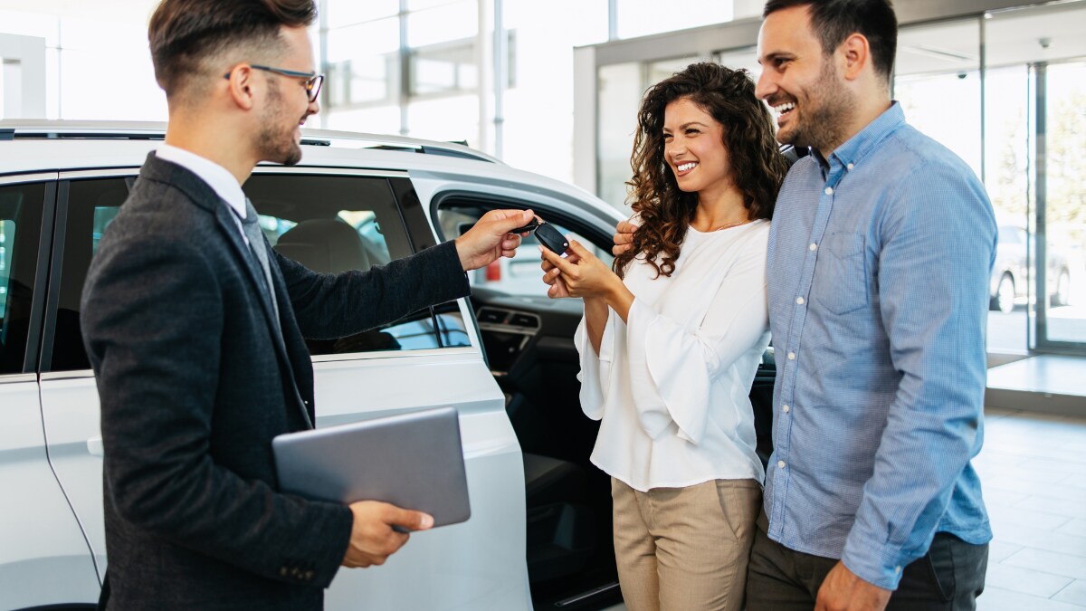 Smiling couple receiving the keys to their new vehicle Smiling couple receiving the keys to their new vehicle
