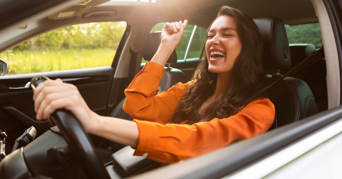 Overjoyed young woman enjoying her new vehicle Overjoyed young woman enjoying her new vehicle