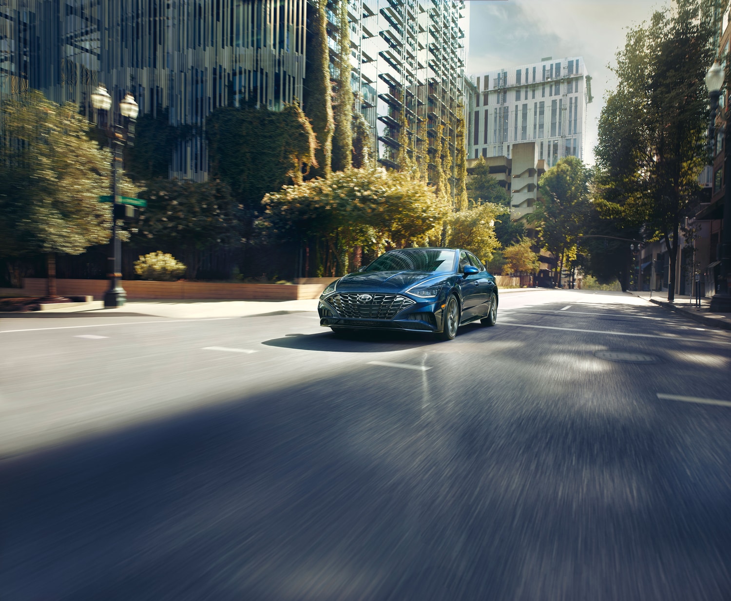 2023-Hyundai-Sonata-Limited-Sedan-L01.png blue Hyundai Sonata hybrid driving through a downtown area