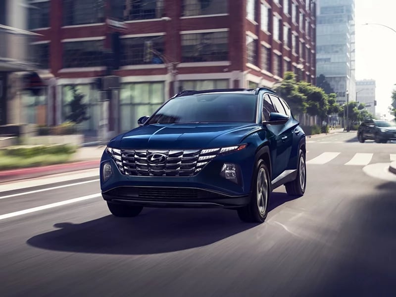 dark blue Hyundai Tucson driving in a downtown area