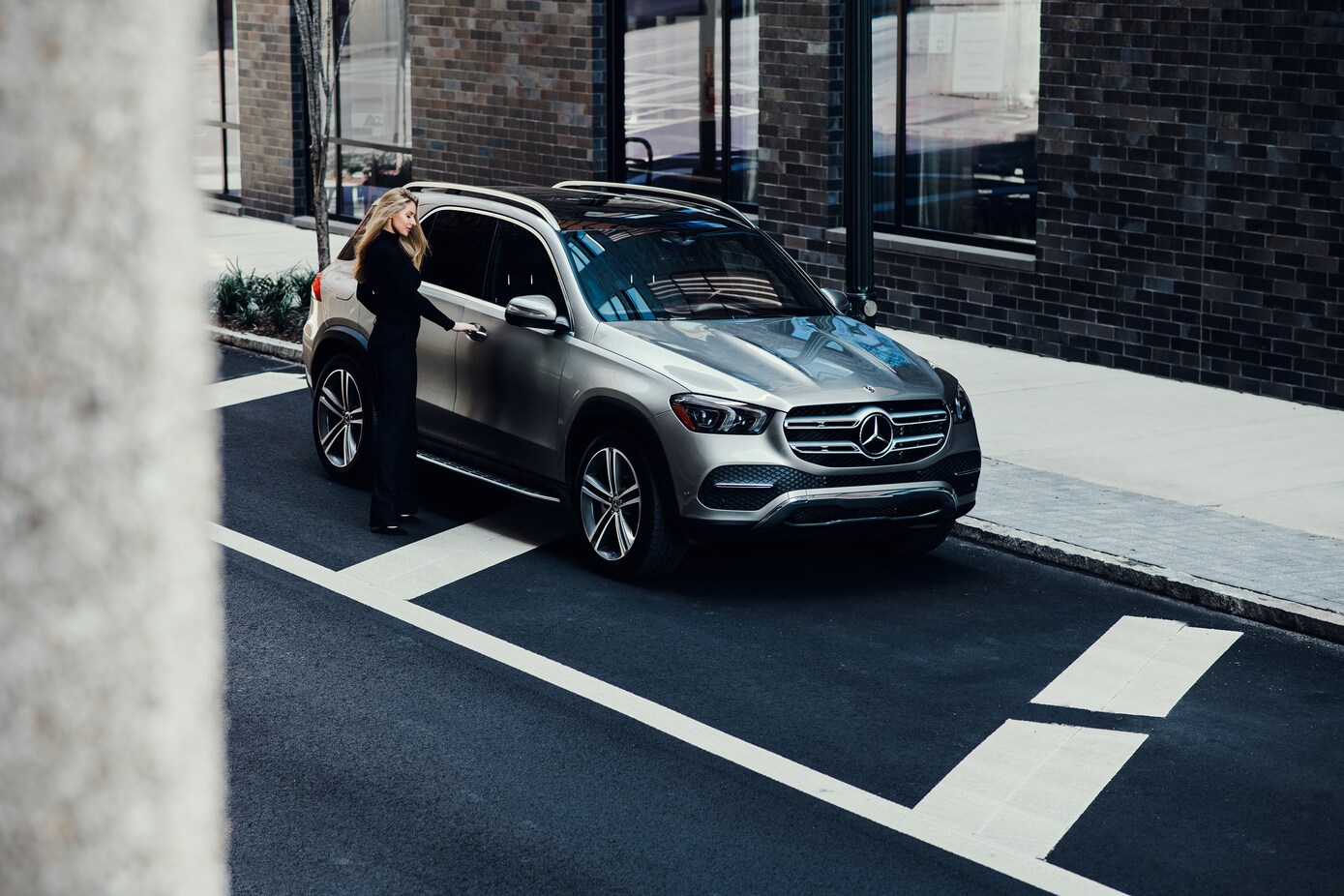 Mercedes-Benz GLE silver Mercedes-Benz GLE with woman dressed in black reaching to open a door