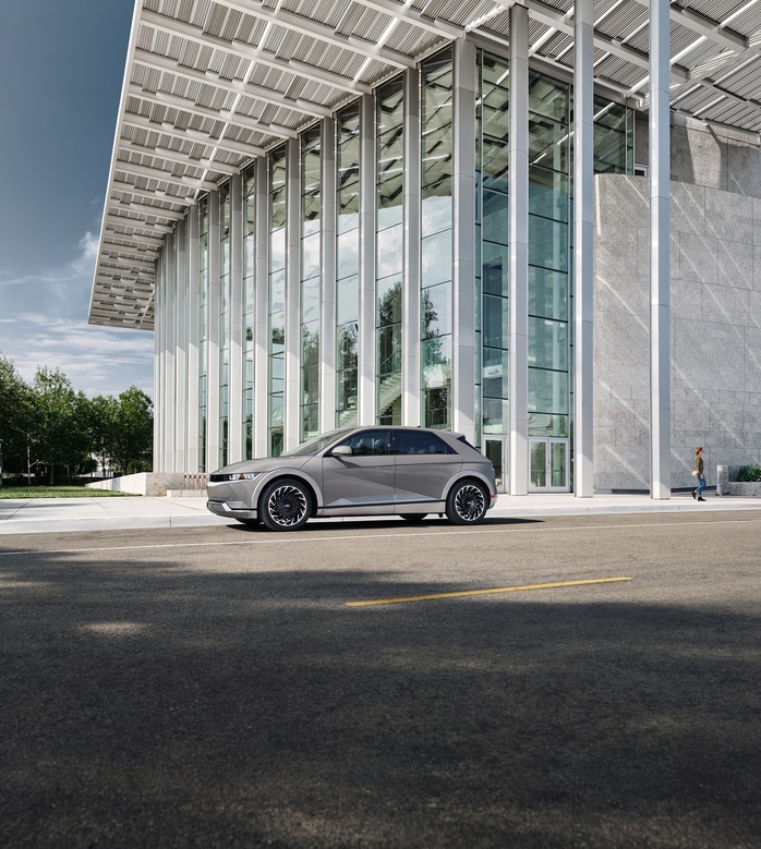 2022-Hyundai-IONIQ5-Limited-SUV-L15.png white Hyundai IONIQ 5 electric SUV parked in front of a white glass building