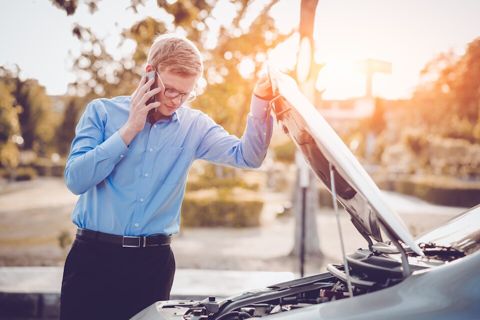 Man on phone looking at car engine_service and roadside assistance.jpeg