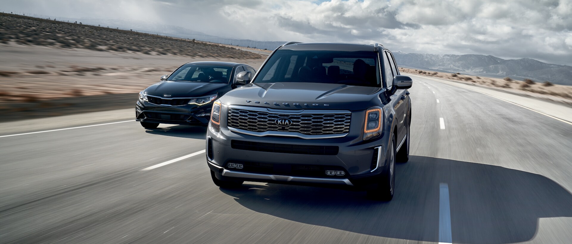 Kia of New Bern is a Car Dealership in New Bern near River Bend, NC | Silver 2020 Telluride Off-Roading Kia of New Bern is a Car Dealership in New Bern near River Bend, NC | Grey 2020 Telluride and Black 2020 Forte driving with mountains in distance