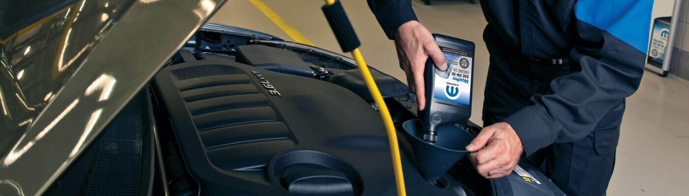 Mopar mechanic filling engine oil
