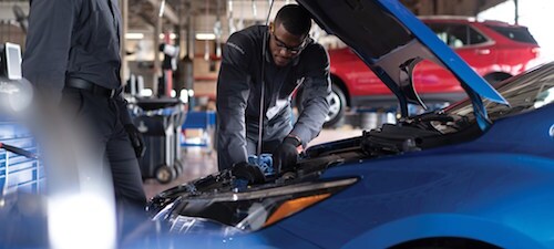 Kriegers Collision Center Two service technicians working under the hood of a car