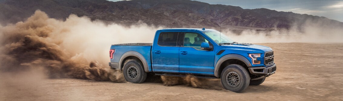 Blue Ford F-150 passenger side view driving in desert