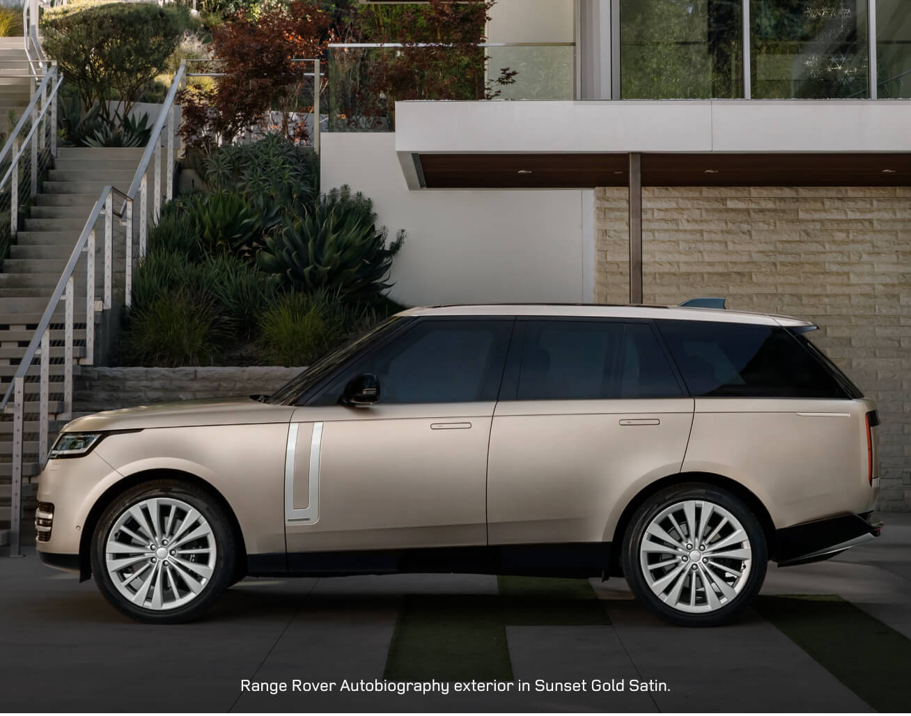 Side view of a Range Rover Autobiography in Sunset Gold Satin parked outside a villa.