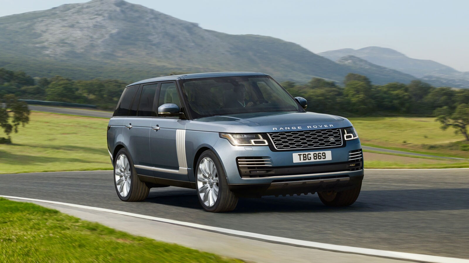 New Range Rover driving down road with mountain backdrop