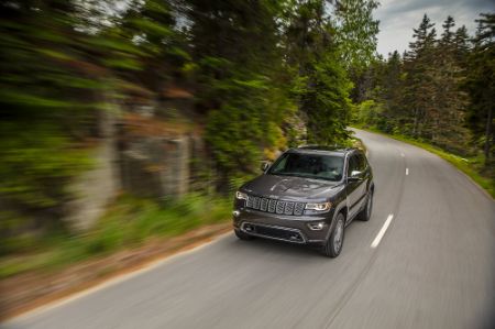 Jeep Grand Cherokee white Jeep Grand Cherokee driving towards camera with headlights on