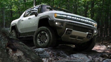 gmc_white_hummer_ev_driving_on_rocks_through_forest.jpeg