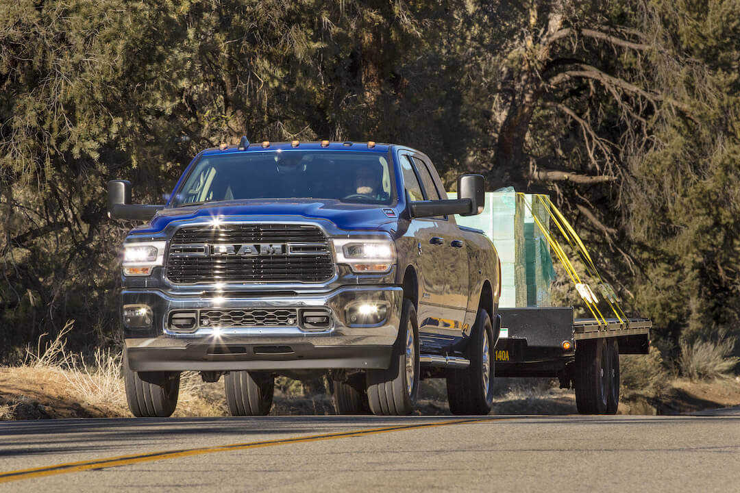 Vue 3/4 avant d'un RAM 2500 HD Big Horn Mega Cab 2019 remorquant un trailer de marchandises