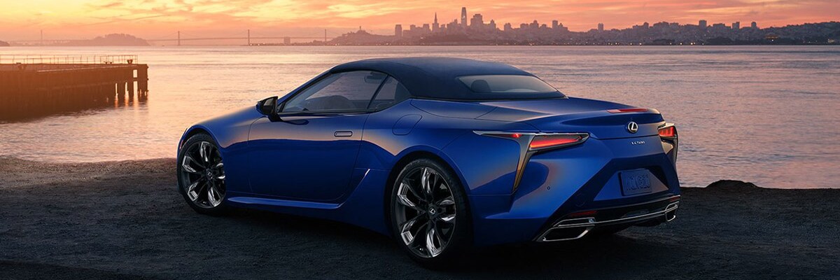 Lexus LC Ultrasonic Blue Mica Convertible parked by a lake with a view of the city skyline.