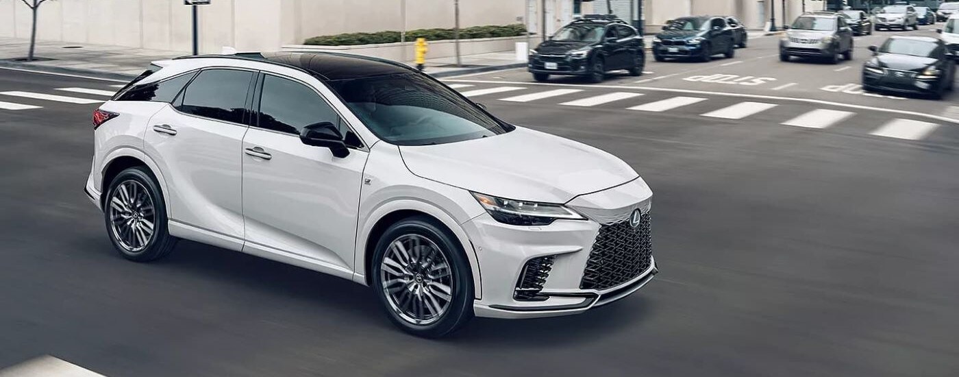 White 2023 Lexus RX driving through an intersection.