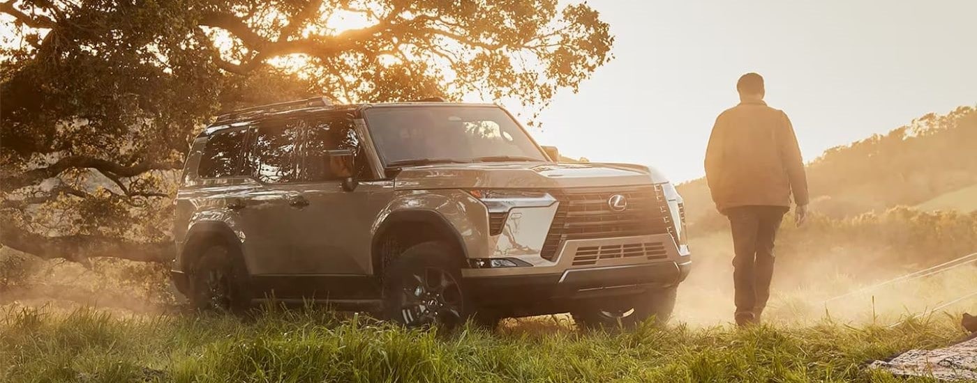 2024%20Lexus%20GX%20-%20Mist.jpg A person walking up to their beige 2026 Lexus GX