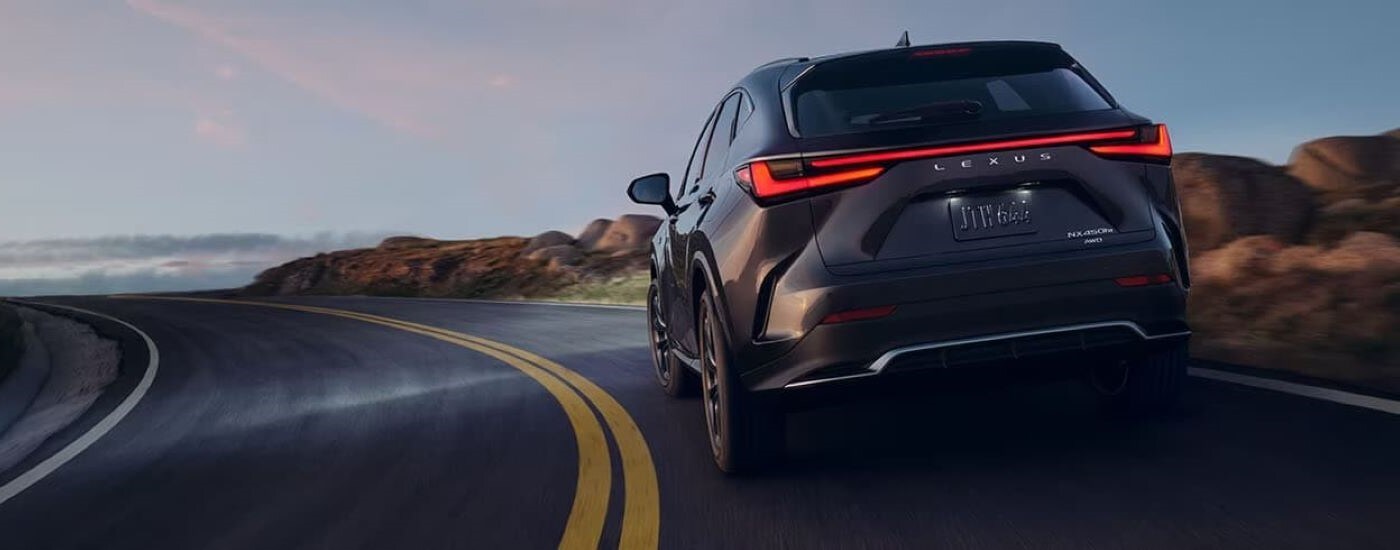 Black 2024 Lexus NX 450h+ driving around a bend.