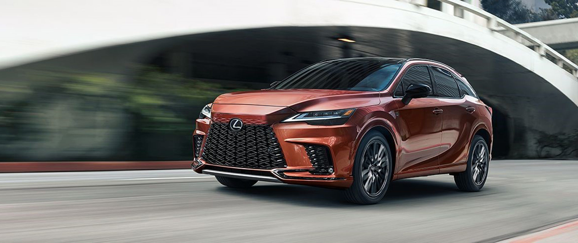 2025 Lexus RX Trim Comparison Orange 2025 Lexus RX driving by a bridge
