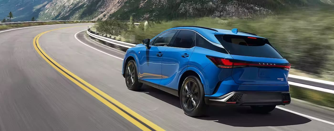Lexus RX 350 Lease - 2023 Lexus RX 350 - Blue.jpg A blue 2023 Lexus RX 350 is shown from a rear angle driving on a winding highway road.