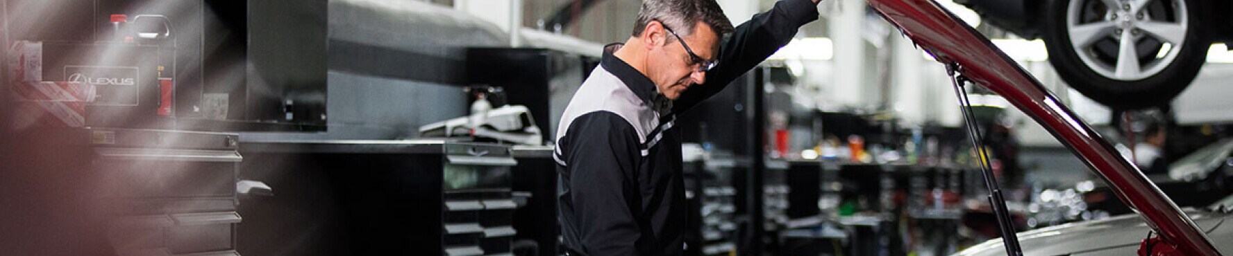 Lexus auto mechanic working under the hood of a vehicle in a Lexus dealership service center