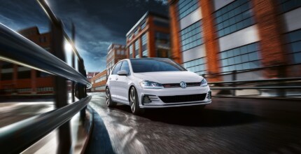 VW Golf GTI white VW Golf GTI driving around a curve