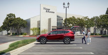Honda CR-V people loading furniture into the trunk of a red Honda CR-V