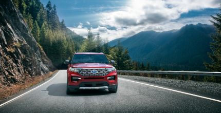 Ford Explorer head on shot of a red Ford Explorer driving on a mountain road