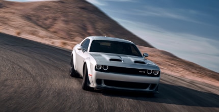 Dodge Challenger white Dodge Challenger rounding a corner on the road