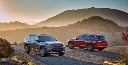 Jeep Grand Cherokee L two Jeep Grand Cherokee L SUVs parked outside with mountains in the background
