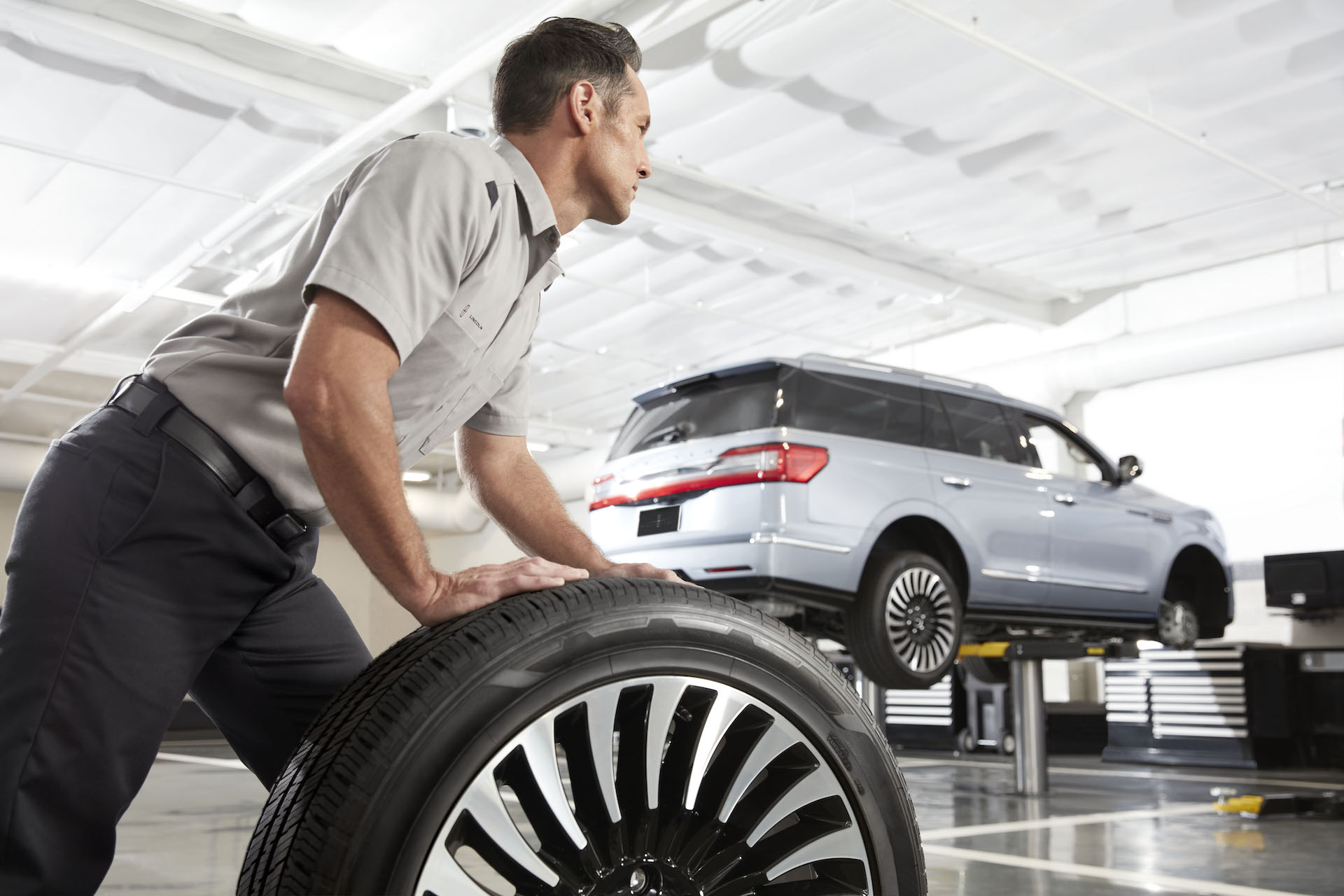 How to check your tires' health at Lincoln of New Bern | Lincoln service technician moving tire in Lincoln service center