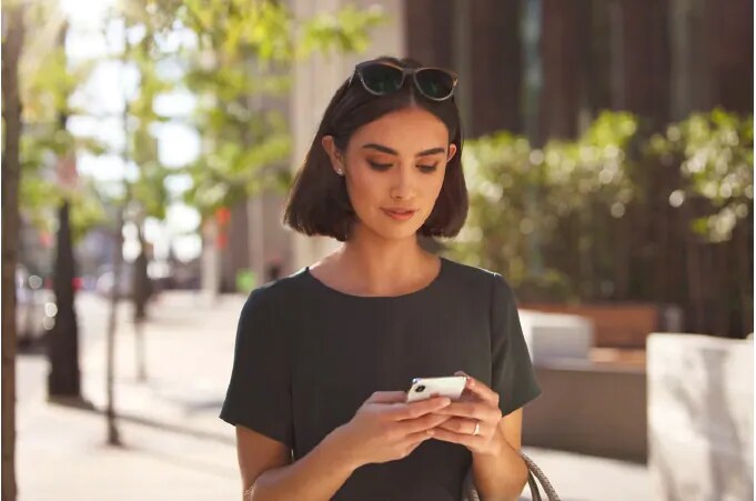 Woman holding phone outside building