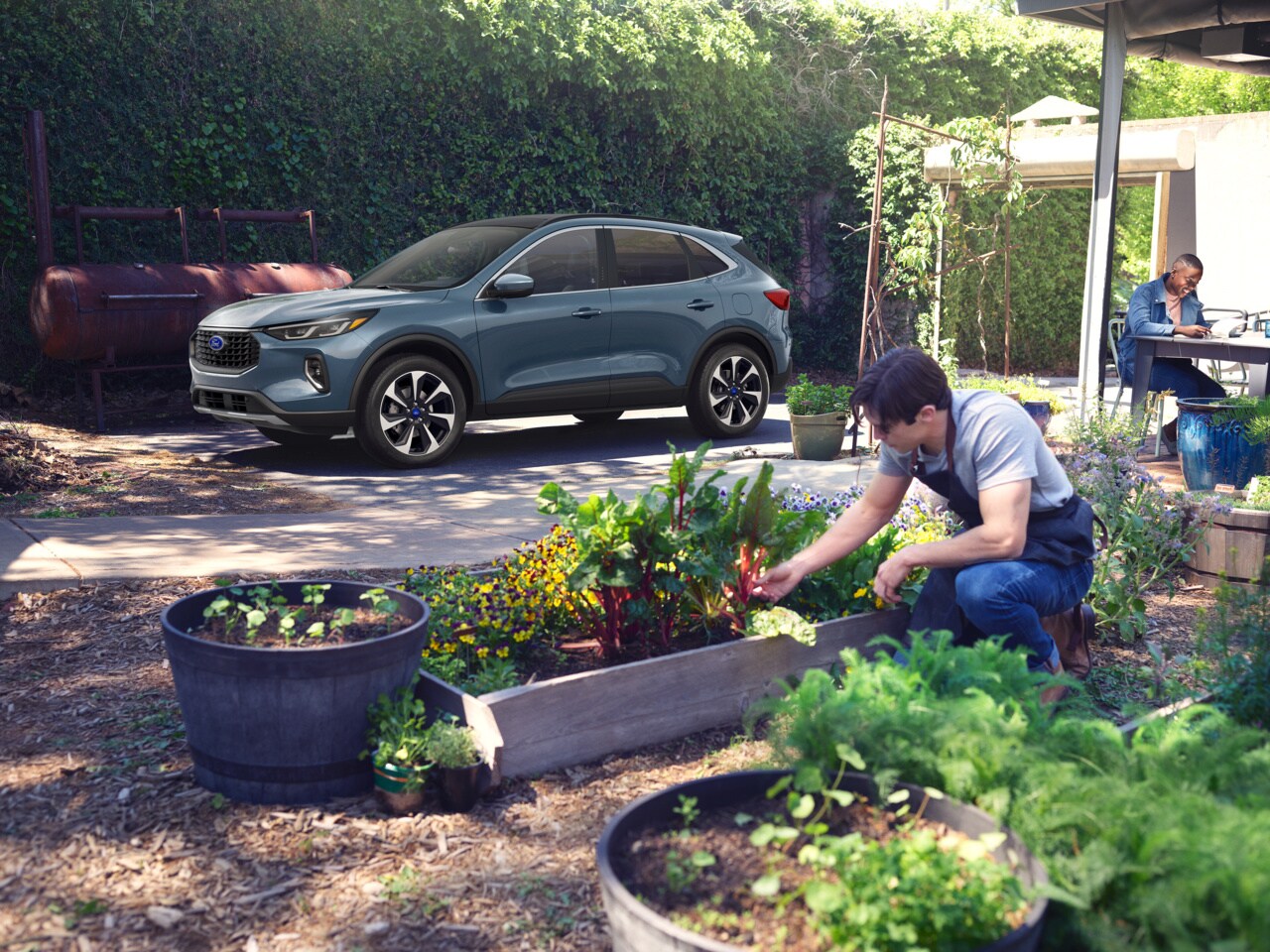 light blue Ford Escape parked in the driveway with a garden and gardener in front