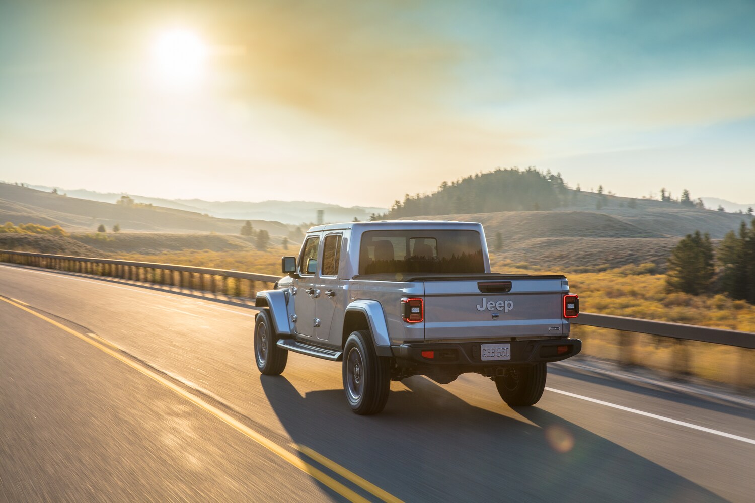 2022-Jeep-Gladiator-Overland-Truck-L10.png silver Jeep Gladiator truck driving down a sunlit road