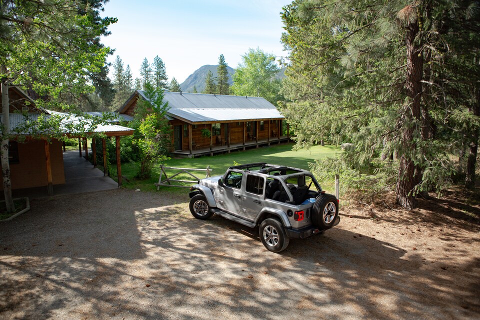 2019-Jeep-Wrangler-JL-UnlimitedRubicon-SUV-L06.png silver Jeep Wrangler SUV parked in front of a cabin