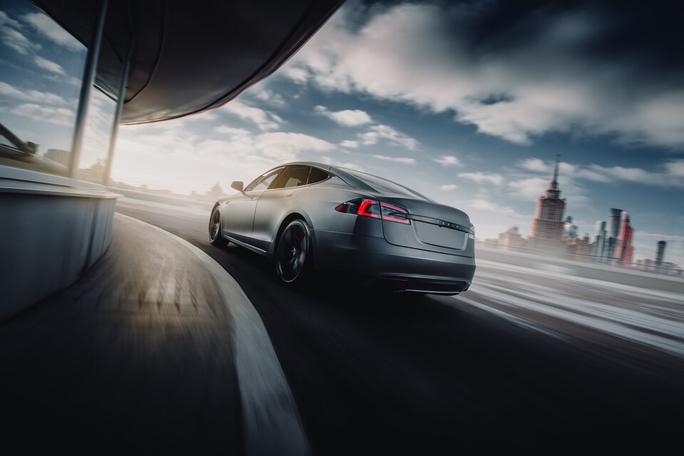 shutterstock_1010369059.png silver 2019 Tesla EV sedan driving around a curved blurred building