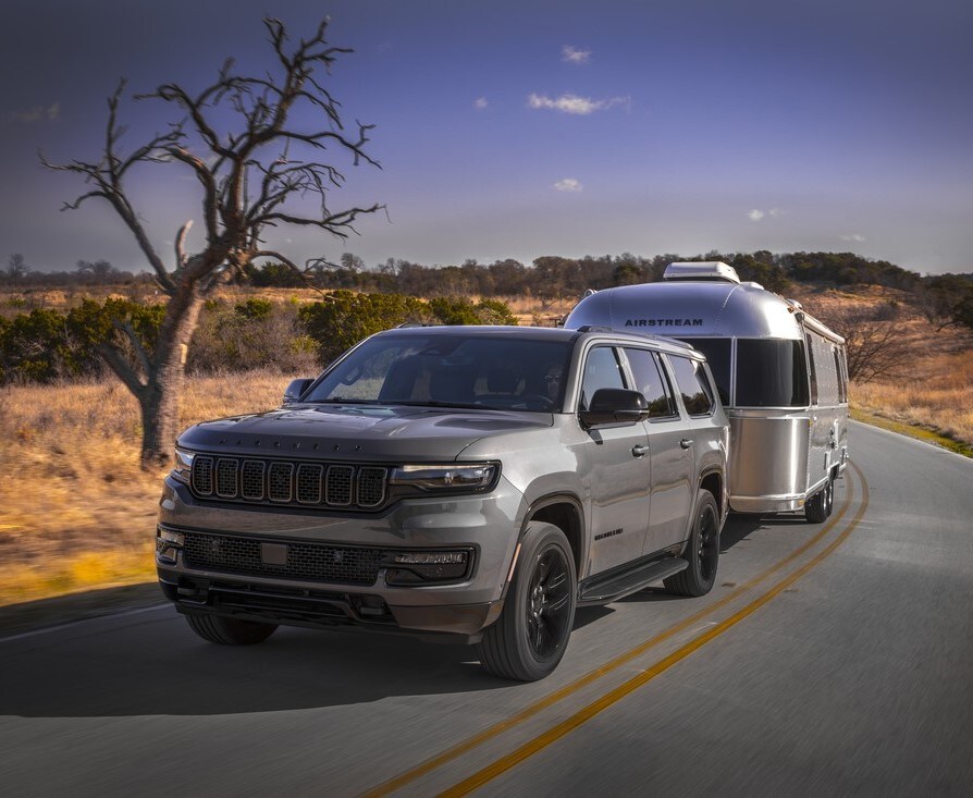 2023 Jeep Wagoneer L.jpg dark gray Jeep Wagoneer L towing an Airstream trailer on the highway