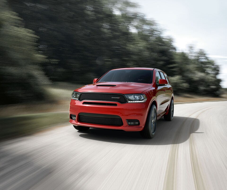 2020-Dodge-Durango-R_T-SUV-L01.png red Dodge Durango SUV driving past blurred greenery