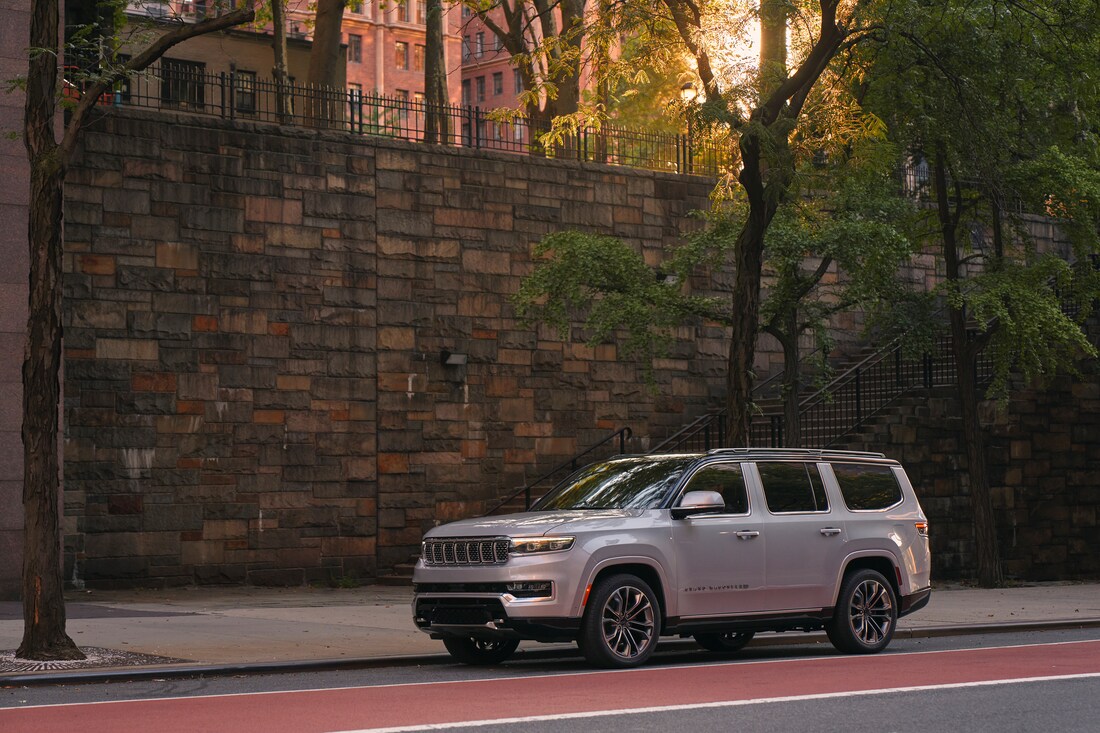2023-Jeep-GrandWagoneer-SeriesIII-SUV-L15.png pearl Jeep Wagoneer parked next to a large stone wall