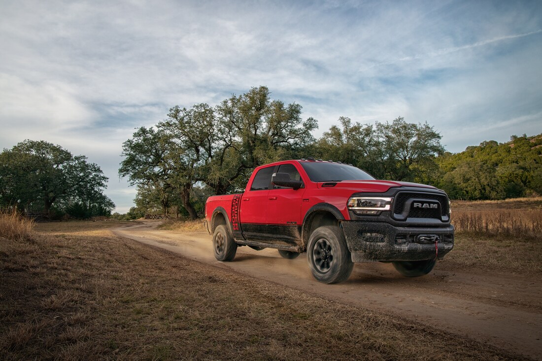 2022-RAM-2500-PowerWagon-CrewCab-Truck-L14.png red Ram 2500 Power Wagon heavy-duty truck driving down a dusty road