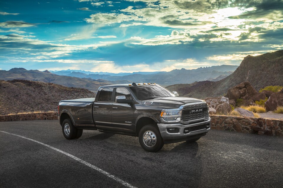 2021-RAM-3500-Limited-CrewCab-Truck-L03.png dark brown Ram 3500 heavy duty truck driving on a desert road