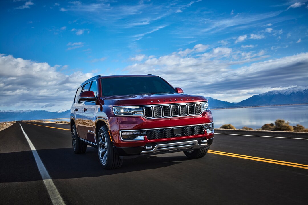 New Jeep Wagoneer red Jeep Wagoneer driving on a road next to a lake and mountains