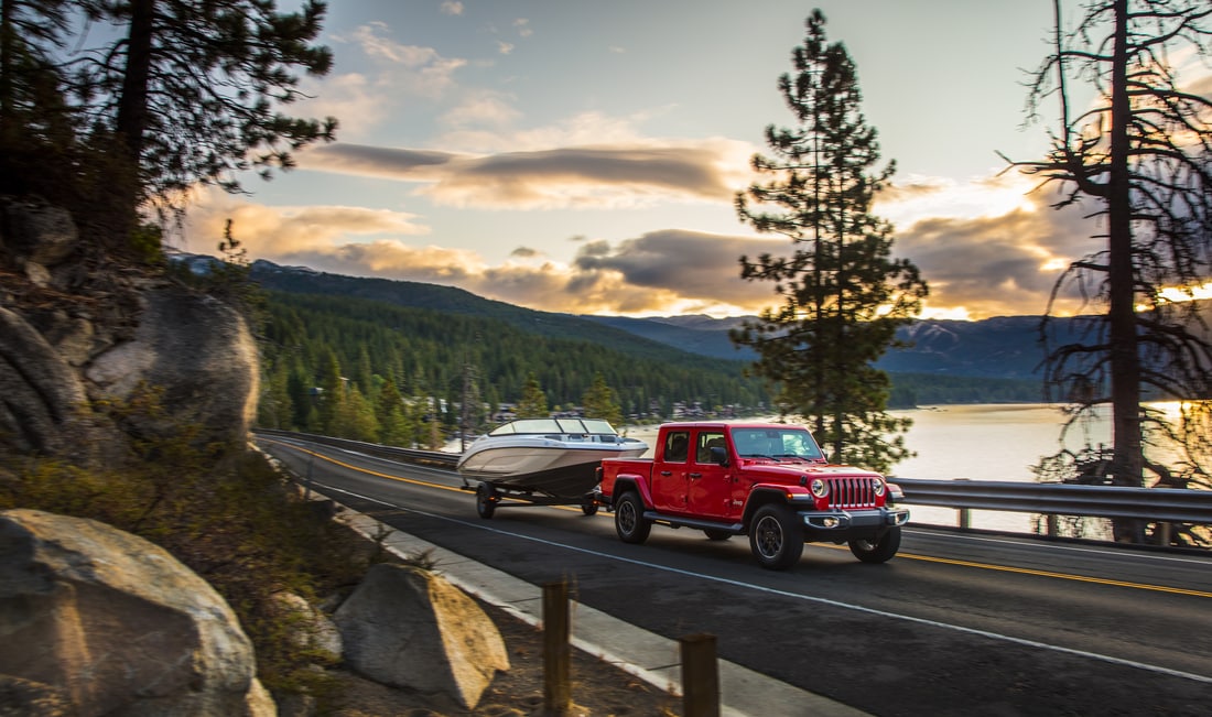 2023-Jeep-Gladiator-Rubicon-Truck-L09.png red Jeep Gladiator truck towing a boat next to a reservoir
