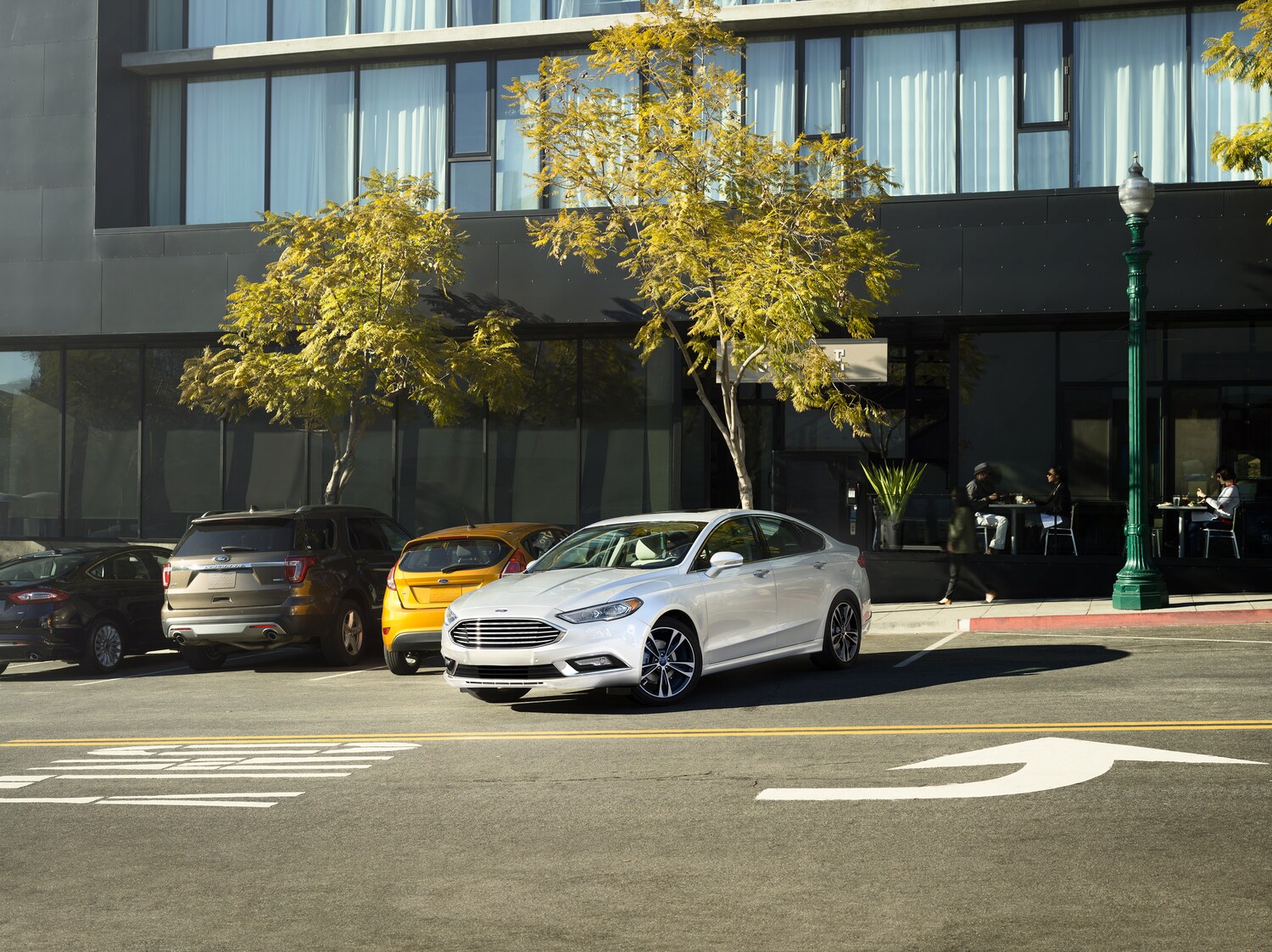 2018-Ford-Fusion-Titanium-Sedan-L01.png white Ford Fusion sedan parked in front of a modern hotel building
