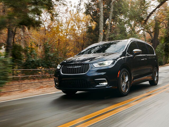 New Chrysler Pacifica for sale near Portland OR A Chrysler Pacifica van driving on a wet road in a forested area