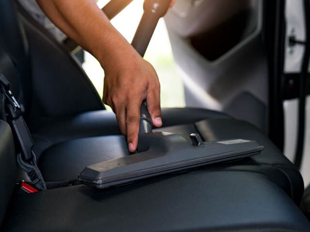 Lithia Chrysler Dodge Jeep Ram FIAT of Spokane Interior Detailing Services A person holding a vacuum cleaning a vehicle seat.
