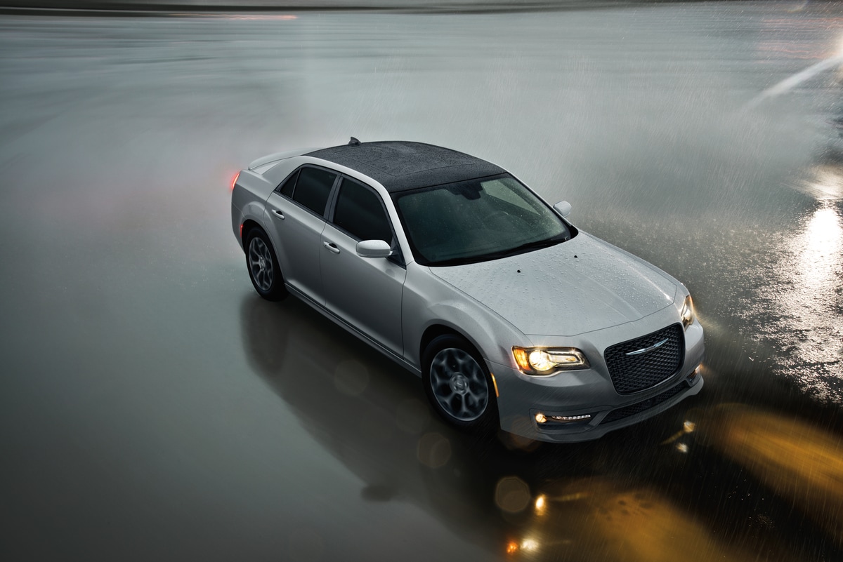 2020-Chrysler-300-C-Sedan-L06.png new Chrysler 300 sedan driving on a rainy day with the headlights on