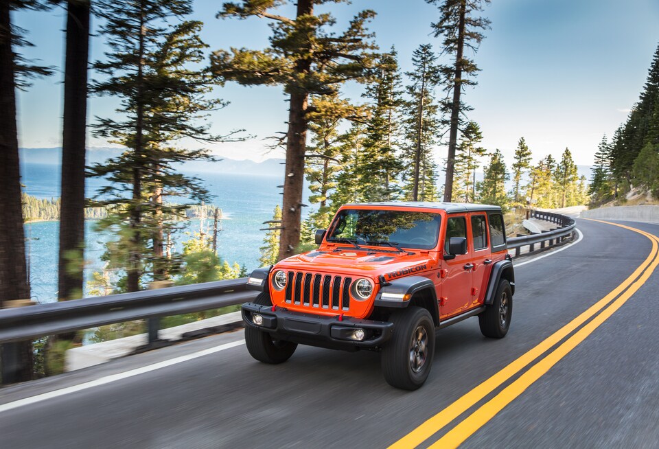2021-Jeep-WranglerJL-Rubicon-Unlimited-SUV-L12.jpeg orange Jeep Wrangler Rubicon Unlimited driving down a coastal highway